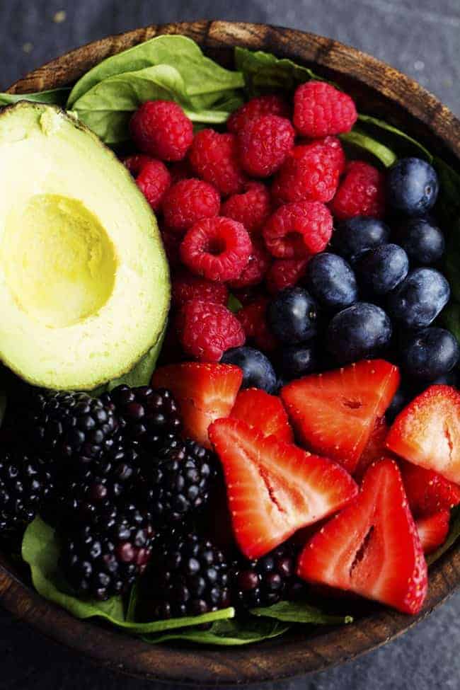 Berry Avocado salad ingredients in a wooden bowl.