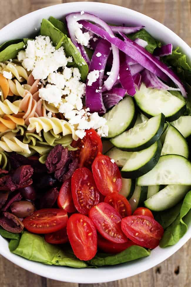 greek spinach pasta salad ingredients in a white bowl.