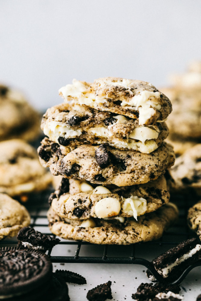 Oreo cookies stacked on top of each other on a cooling rack garnished with oreos surrounding them.