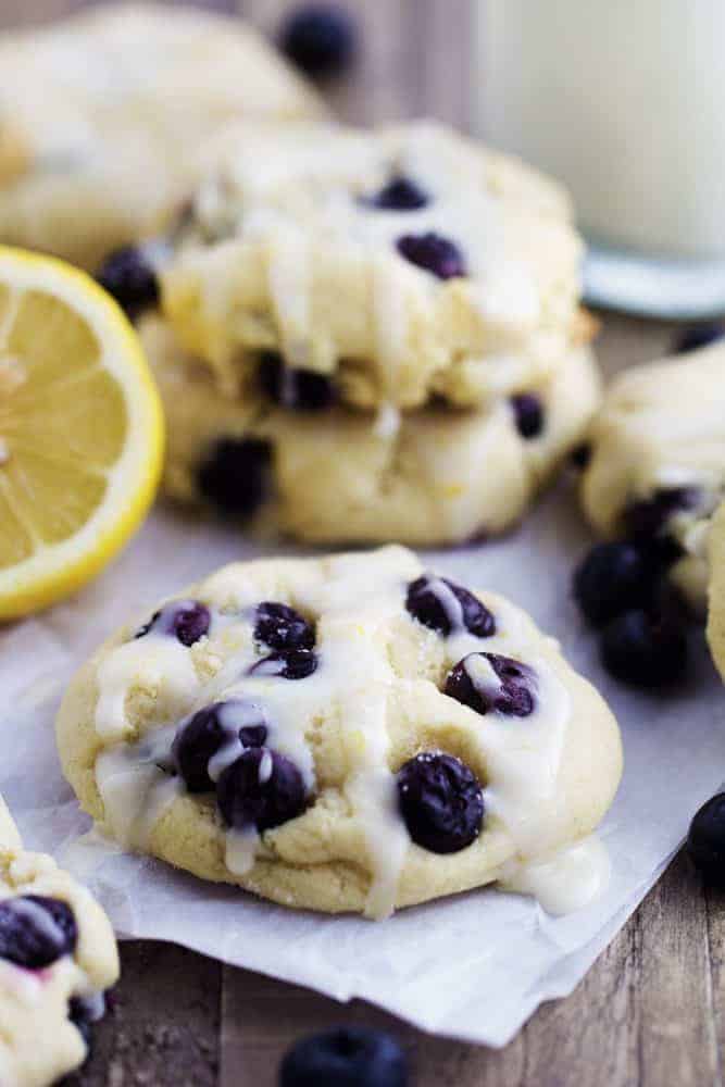 Blueberry cream cheese cookies with a glaze resting on a white paper.