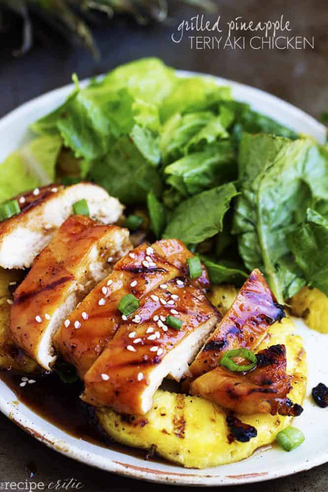 grilled pineapple teriyaki chicken on a white plate with pineapple and salad.