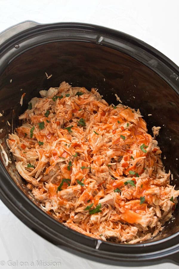 Areal view of Slow Cooker Honey Sriracha Chicken in a black crock pot.