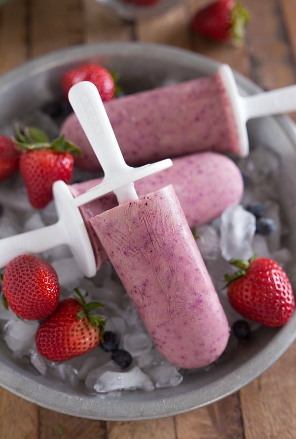 Fruity Greek Yogurt Frozen Pops on top of a bowl of ice and fruit.