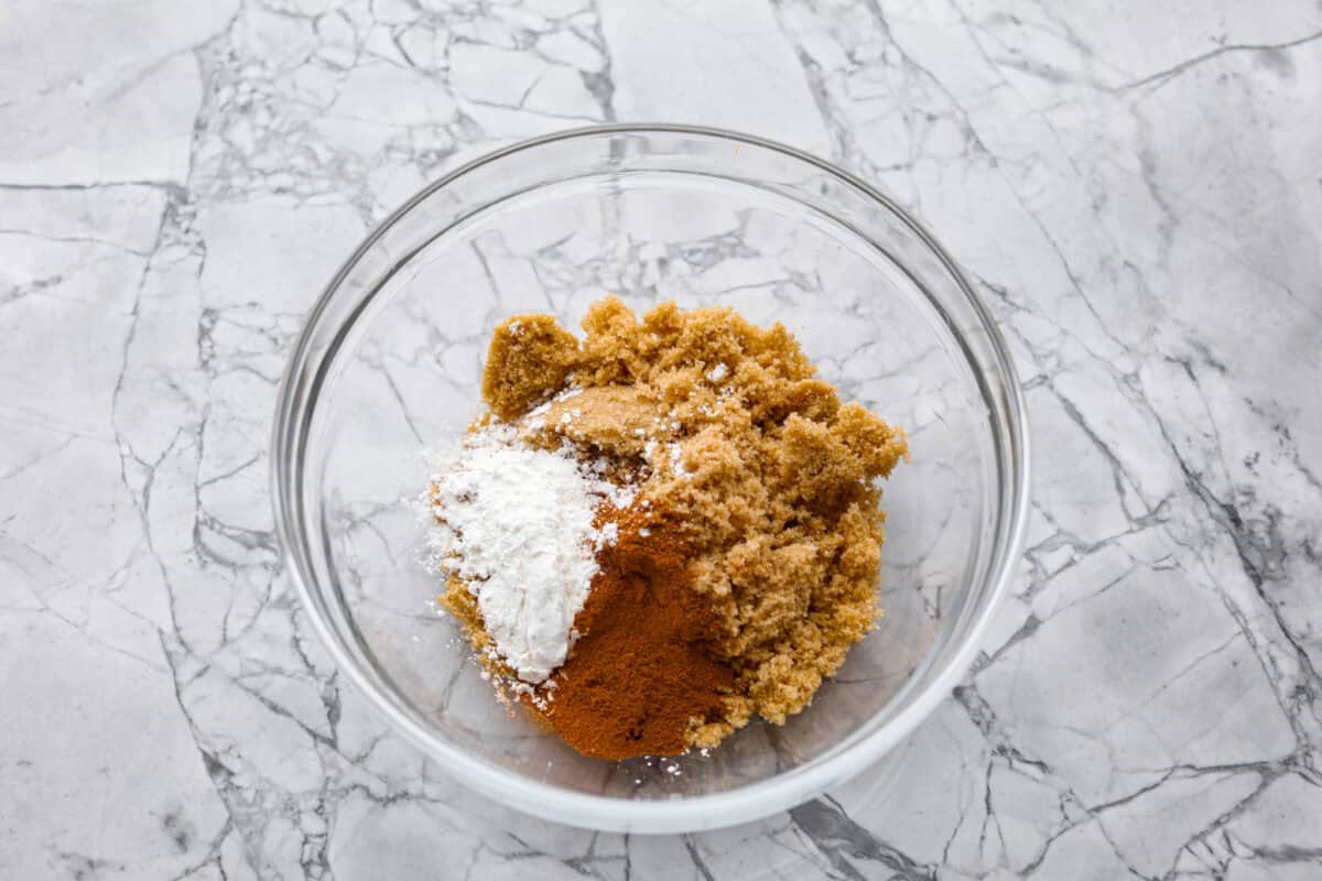 Overhead shot of brown sugar, cinnamon, nutmeg and cornstarch in glass bowl. 