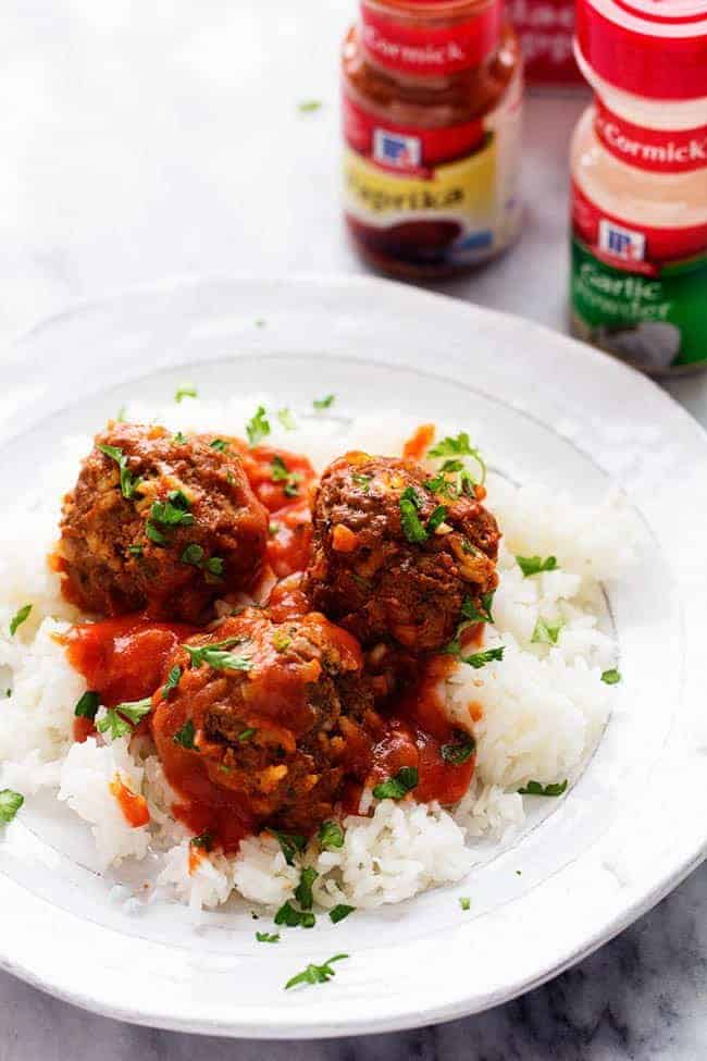 Porcupine Meatballs laying on a bed of rice garnished with chives and mccormick seasoning in the background.