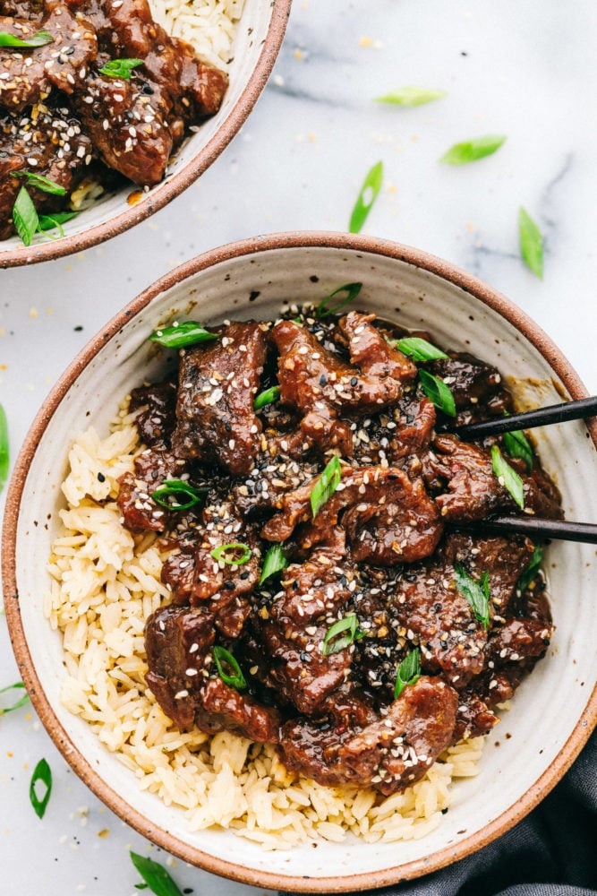 Korean beef over rice in a bowl with two black chopsticks. 