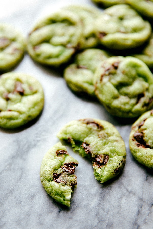 Mint chocolate chip cookies laid out randomly and one broken in half.