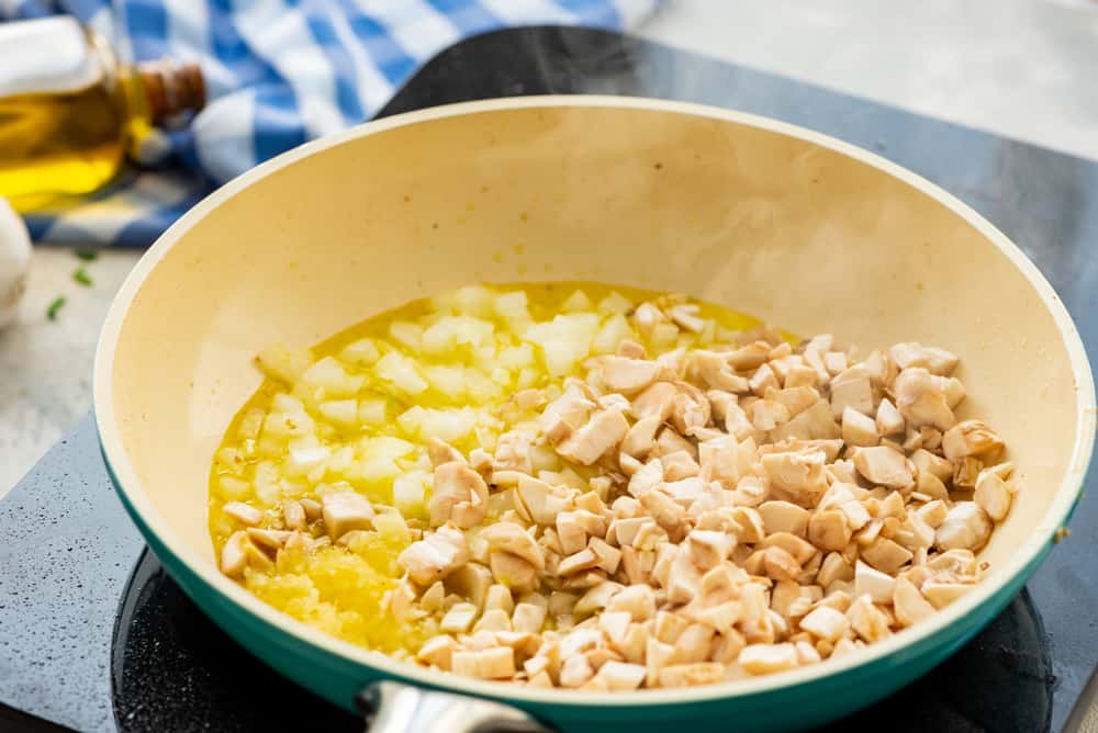 Vegetables being sauteed in a blue and white skillet.