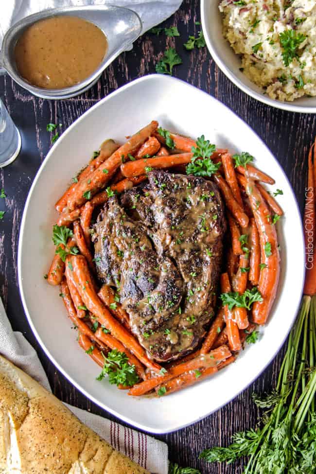 Areal view of roast with carrots on a white plate.