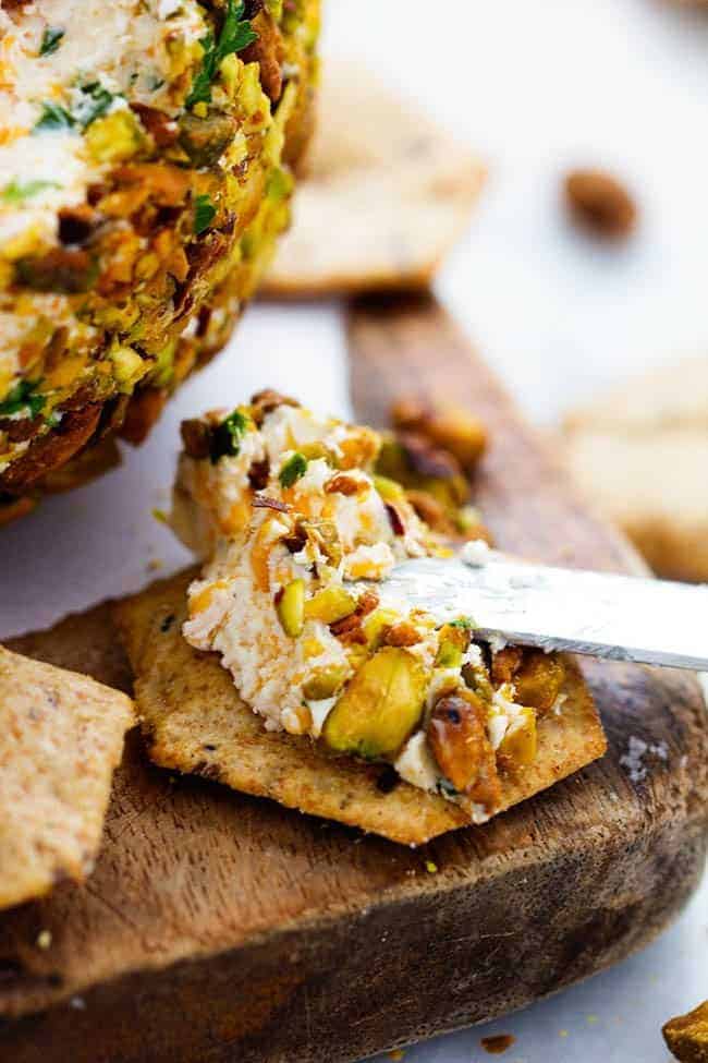 Cheddar Bacon Pistachio Cheeseball with being spread on cracker