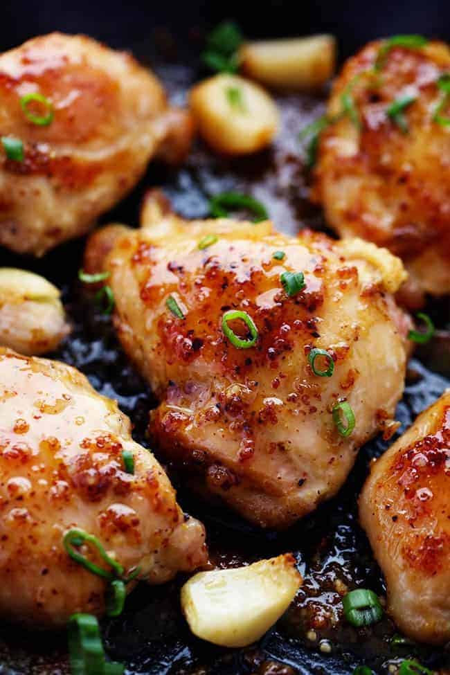 Chicken in frying pan with garlic and onion.