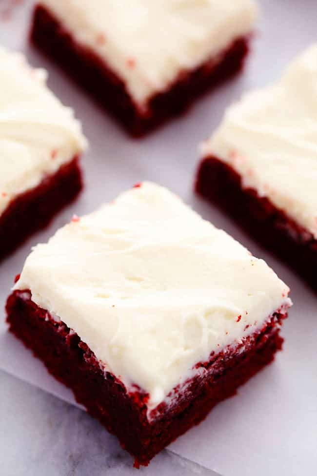 Red Velvet brownies separated cut into pieces on parchment paper.