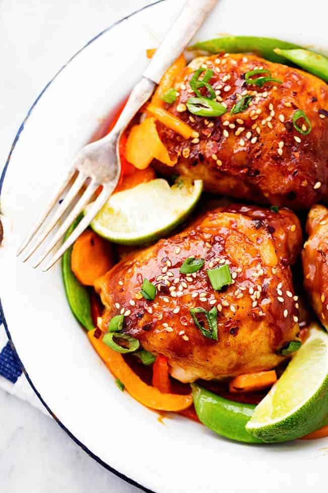 Thai Peanut Skillet Chicken on a white plate with lime and other fresh vegetables.