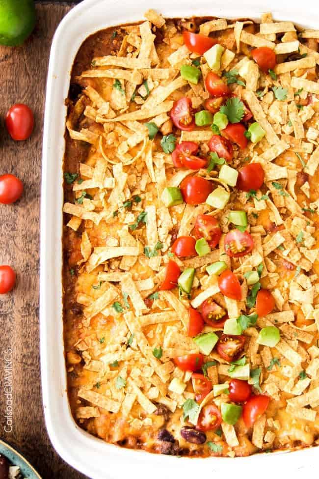 Taco chili pasta bake in a white casserole dish with cherry tomatoes on the side.