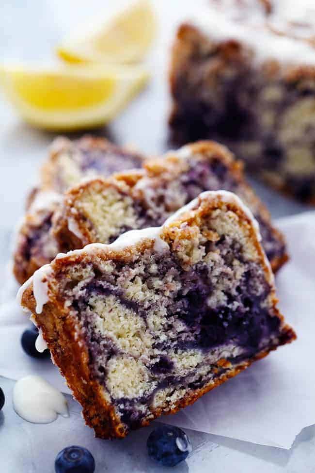 Slices of blueberry pie bread with lemon glaze and fresh blueberries on the side.