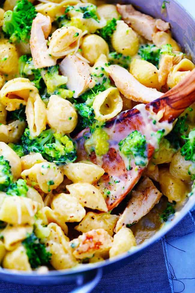 CHEESY CHICKEN BROCCOLI SHELLS IN A BOWL WITH A WOODEN SPOON.  