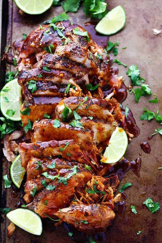 Slow cooker honey lime ginger pork sliced up with fresh cut limes on the side.