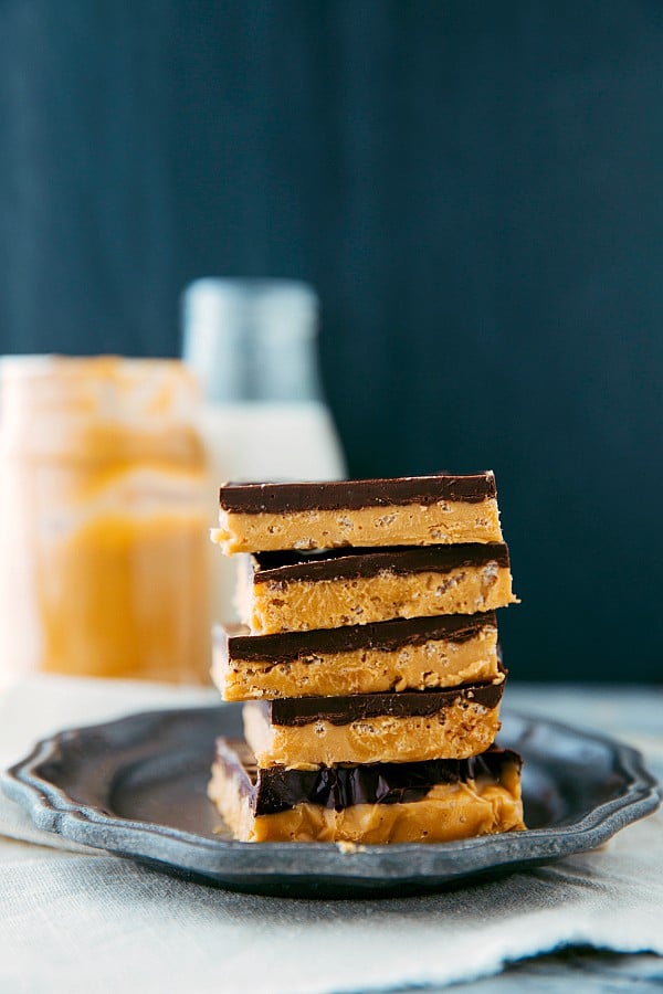 Crunchy peanut butter and chocolate bars stacked on top of one another on a gray plate.