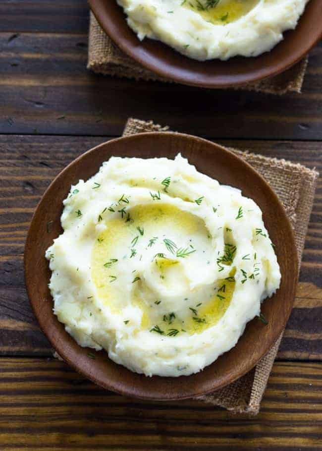 Overhead photo of Slow Cooker Ranch Mashed Potatoes in brown bowls.