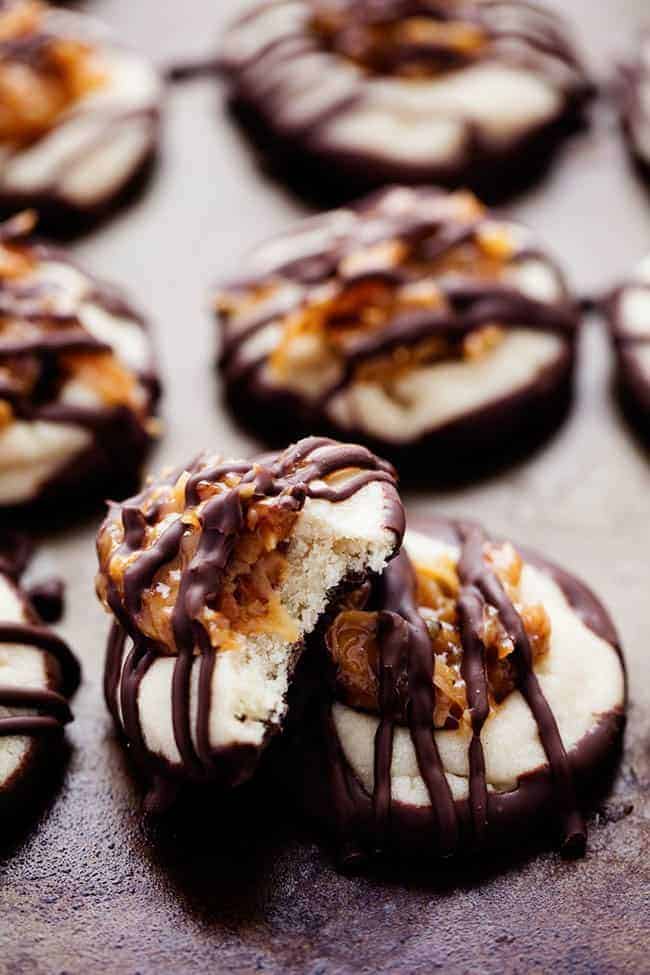 Close up photo of chocolate thumbprint Samoa cookies with one with a bite taken out of it.