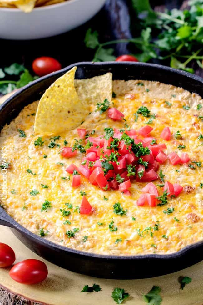 Queso verde corn dip in a large skillet with chips dipped into it. 