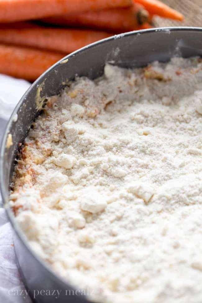 Carrot coffee cake in a round cake pan with crumb topping. 