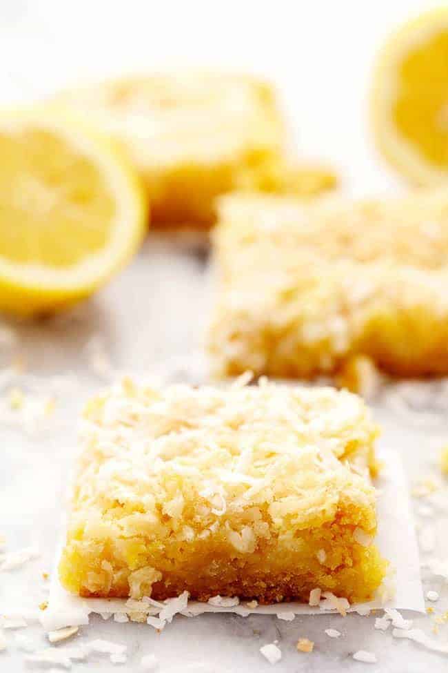 Lemon coconut butter bars with a fresh cut lemon in the background.