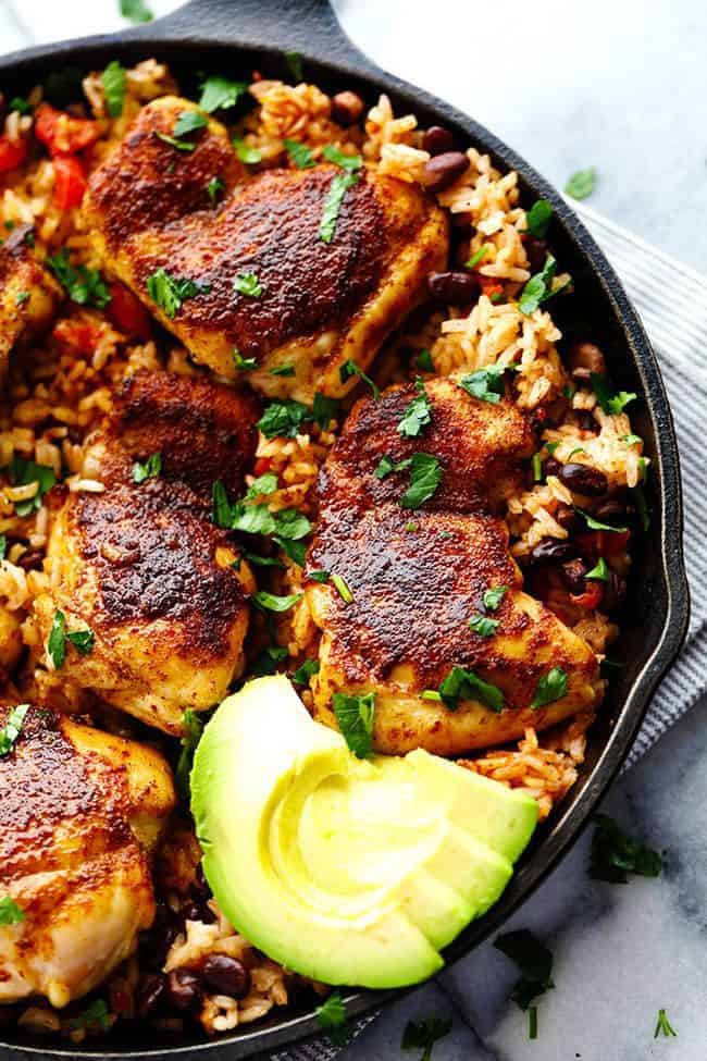 One Pan Southwest Blackened Cajun Chicken with Rice in a skillet with fresh cut avocado on the side. 