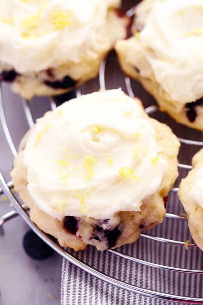 A Blueberry Lemon Cookie with Lemon Cream Cheese Frosting on a cooling rack. 