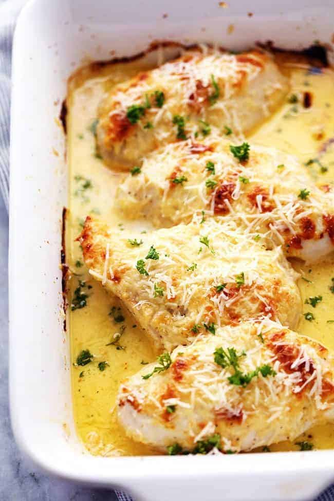 Creamy baked asiago chicken in a white casserole dish. 