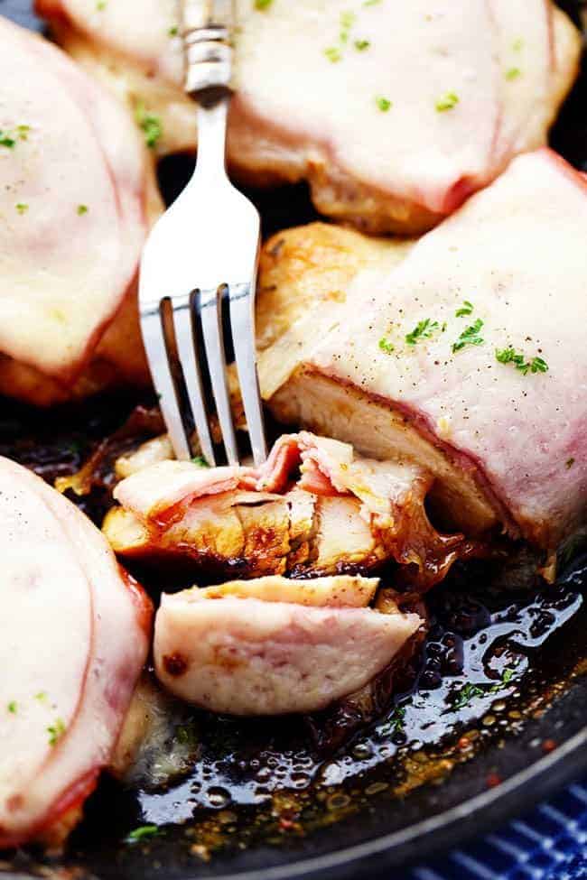 A fork taking a piece of Honey Dijon Ham and Swiss Chicken out of a skillet. 