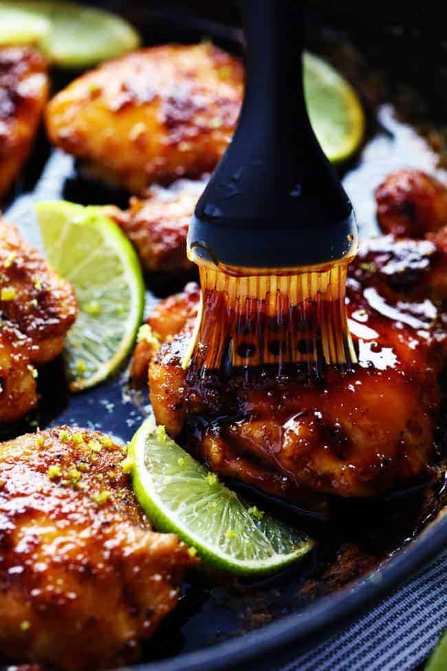 Chicken being basted with honey in a skillet. 