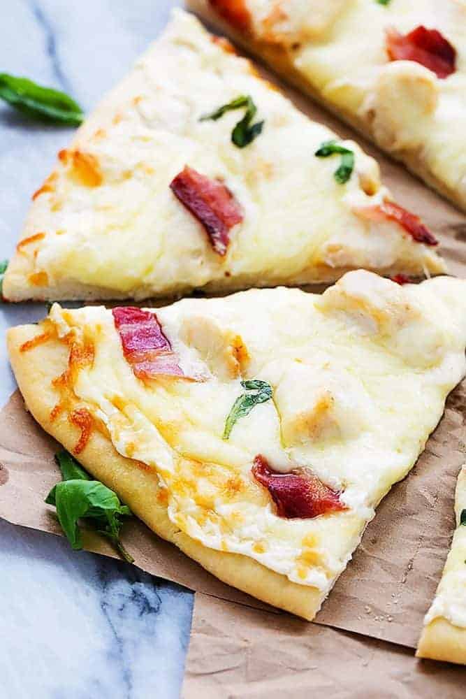 Bacon Chicken Alfredo Pizza that has been sliced for eating. 