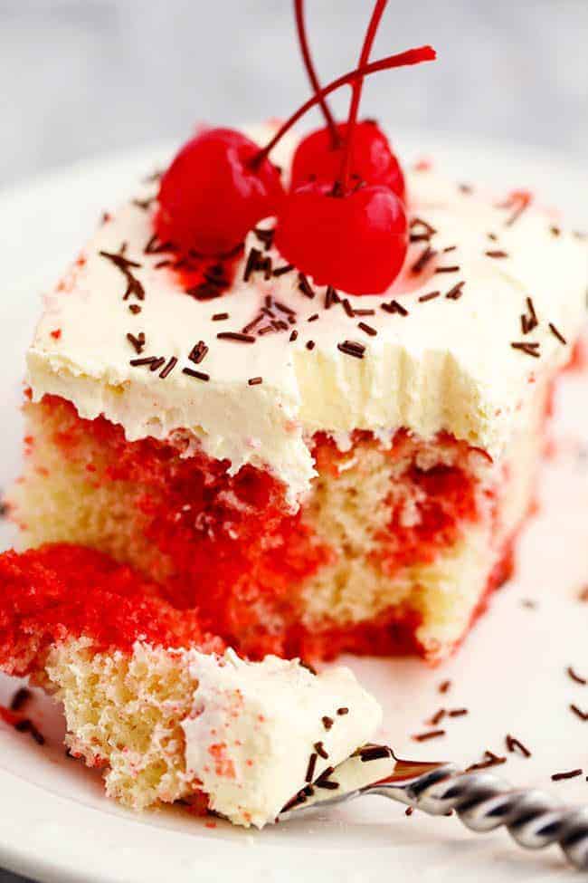 Cherry Jello Coke Poke Cake on a white plate with a bit taken out of it. 