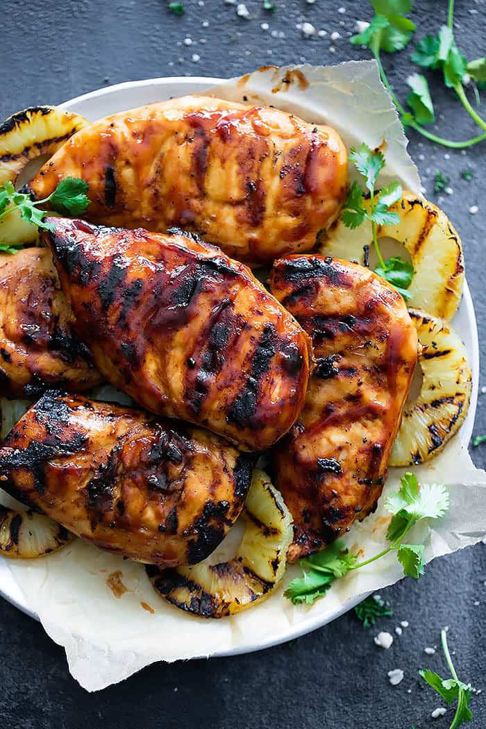 Grilled Hawaiian BBQ Chicken on a white plate with fresh pineapple rings. 