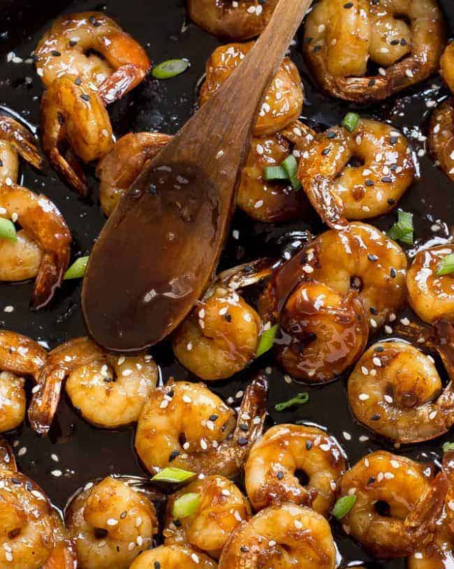 Hoisin Shrimp in a skillet with a wooden spoon. 