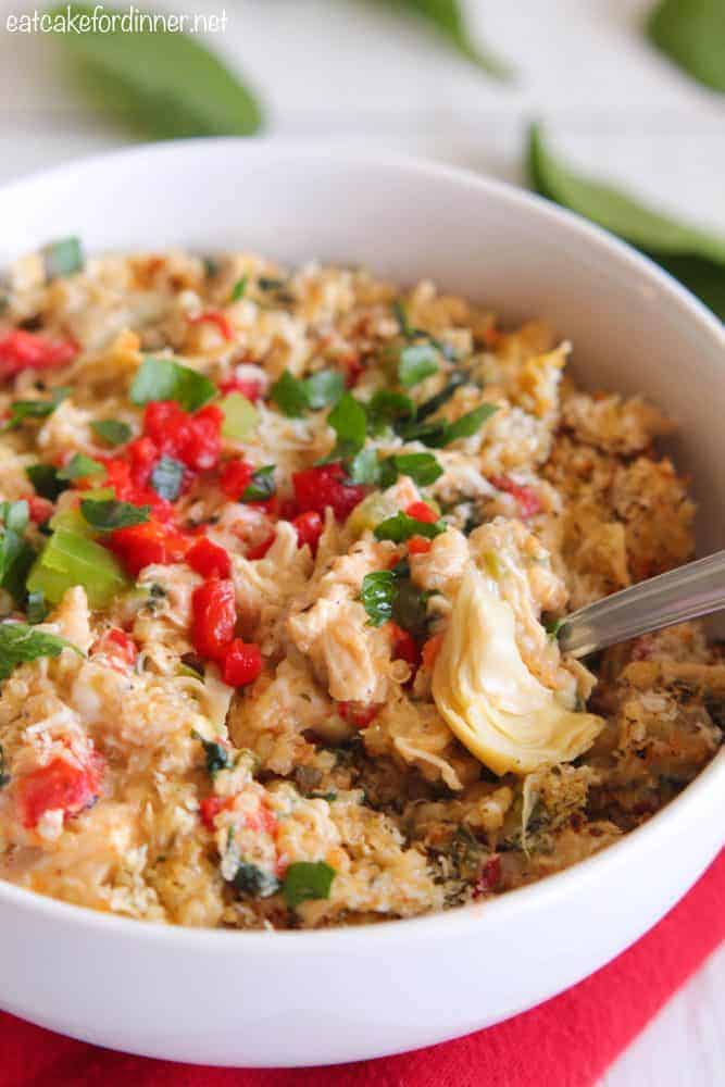 Creamy Spinach and Artichoke Chicken Quinoa in a white bowl with a metal fork. 