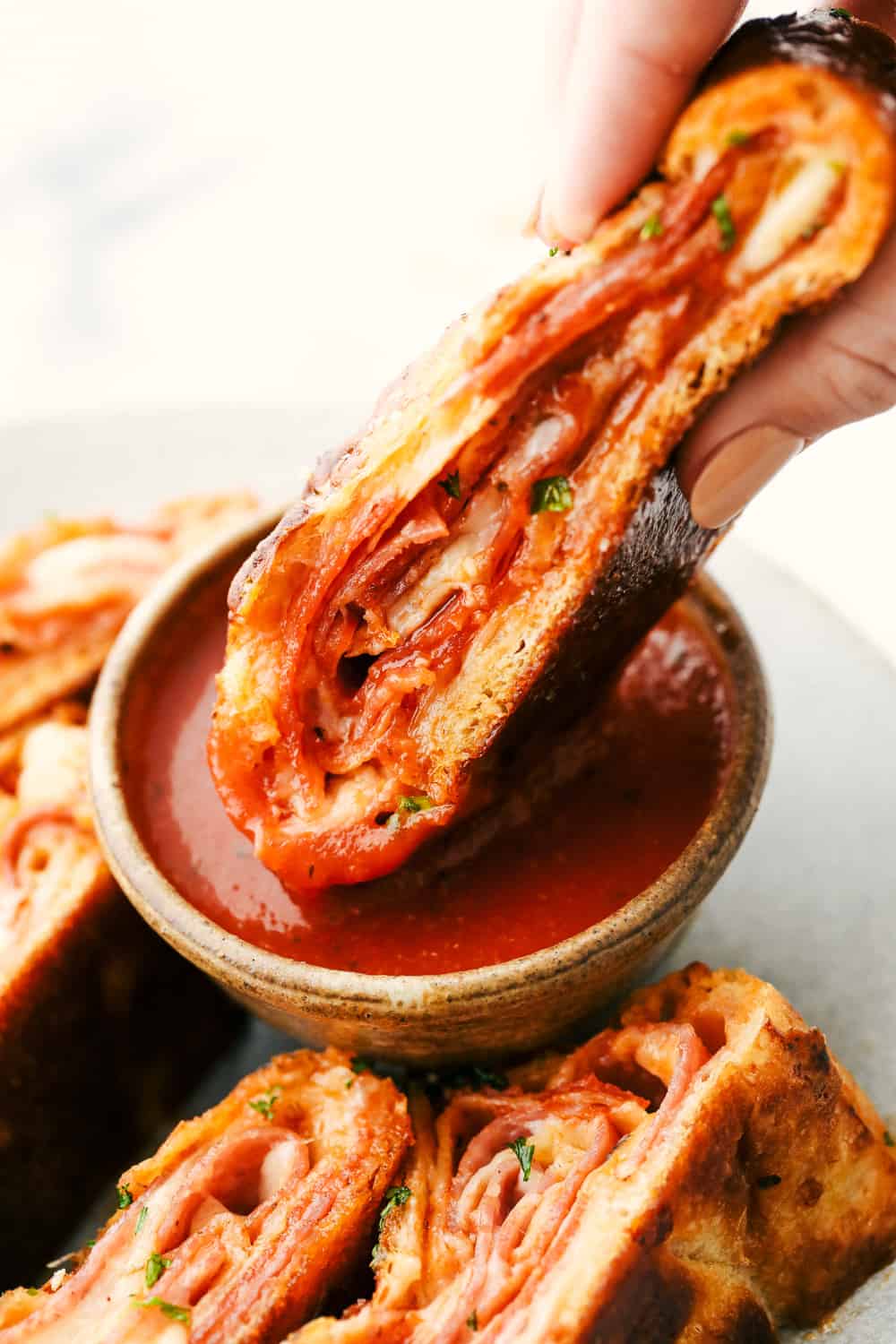 Stromboli slice being dipped in the marinara sauce. 