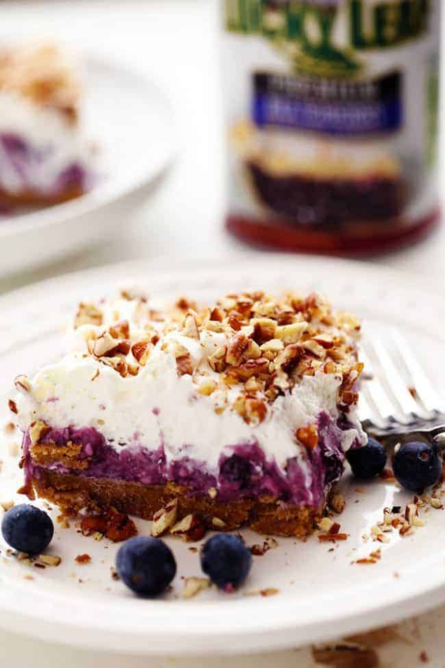 No Bake Creamy Blueberry Pecan Square on a white plate with a metal fork and fresh blueberries. 