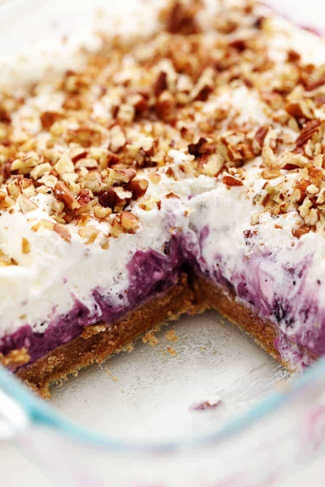 No Bake Creamy Blueberry Pecan Squares in a clear pan with one square removed. 