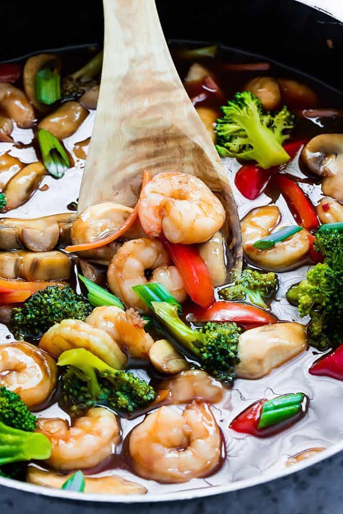 Wonton Shrimp Stirfry in a large pan with a wooden spoon. 