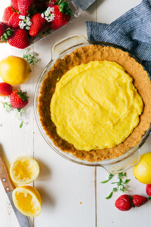 Lemon filling in the pie with fresh strawberries and lemons on the side. 