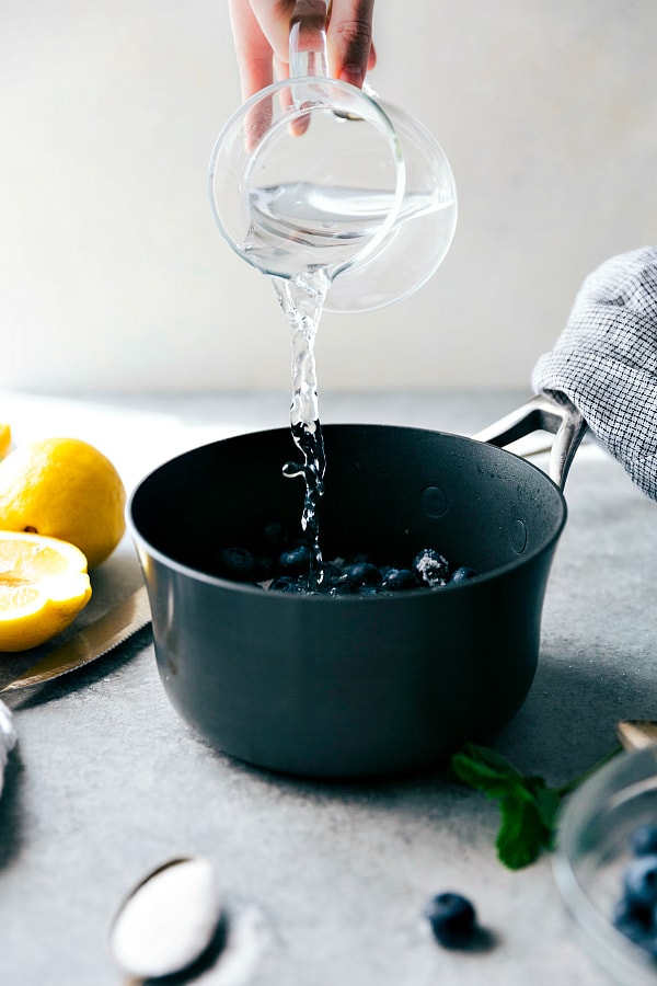 Water being added to a pot with fresh lemons on the side. 