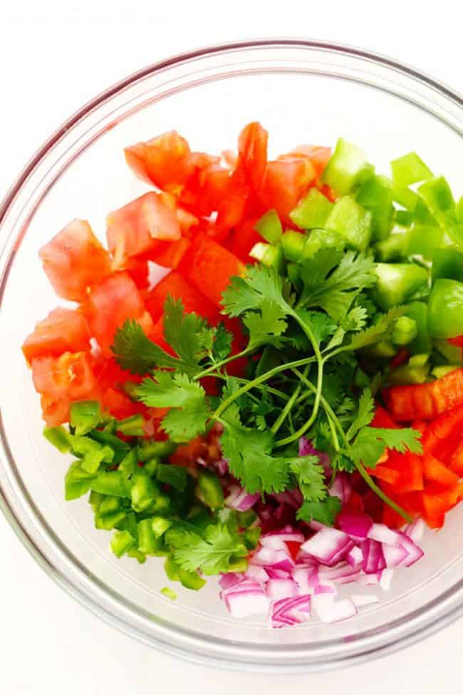 Ingredients for Slow Cooker Restaurant Style Garden Salsa in a clear bowl. 