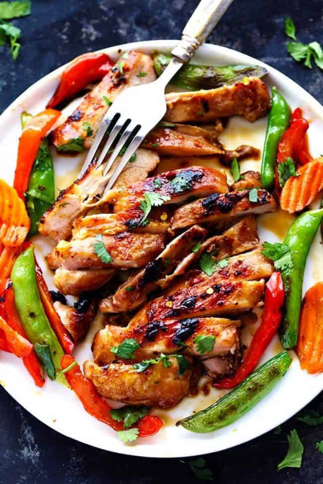 Thai Barbecue Chicken on a white plate with a metal fork. 