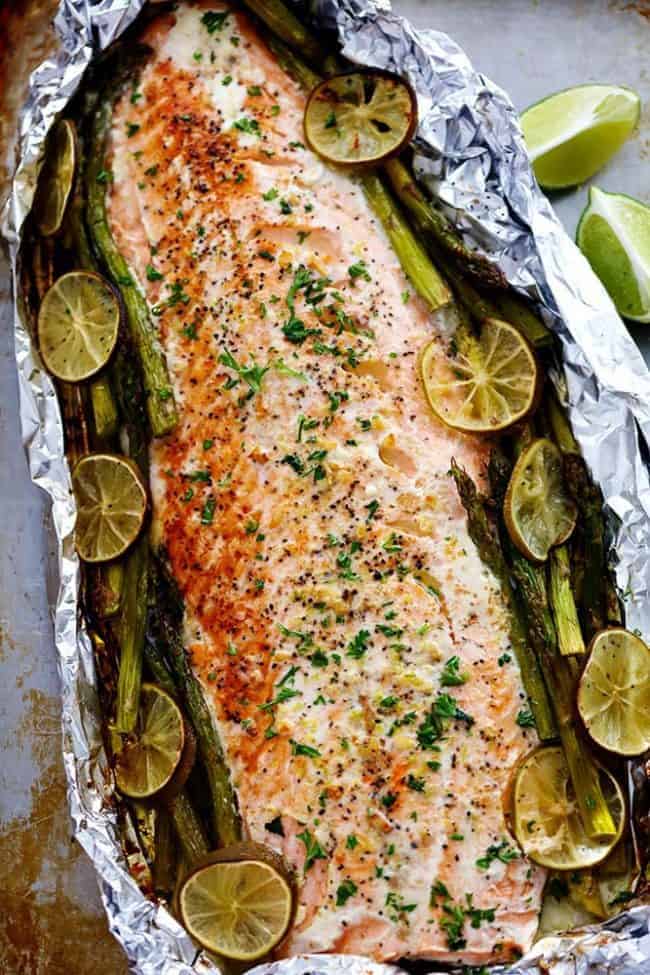 Overhead photo of Buttery Garlic Lime Salmon with Asparagus in Foil with fresh cut limes on the side. 