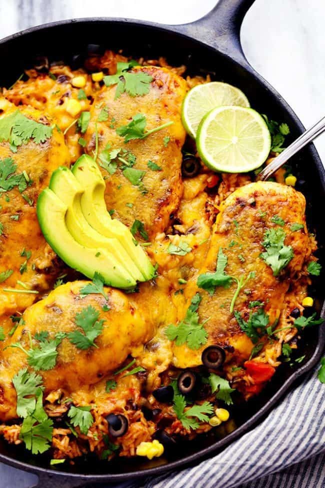 Cheesy Fiesta Chicken and Rice Skillet with freshly sliced avocado and limes on top. 