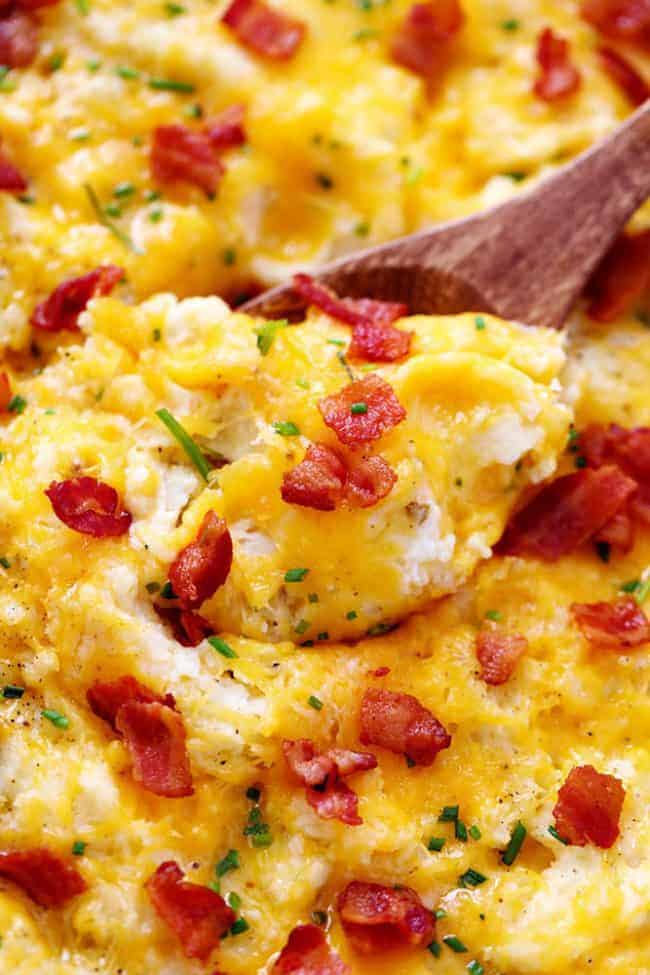 Upclose photo Cheddar Garlic Mashed Potato Casserole with a wooden spoon. 