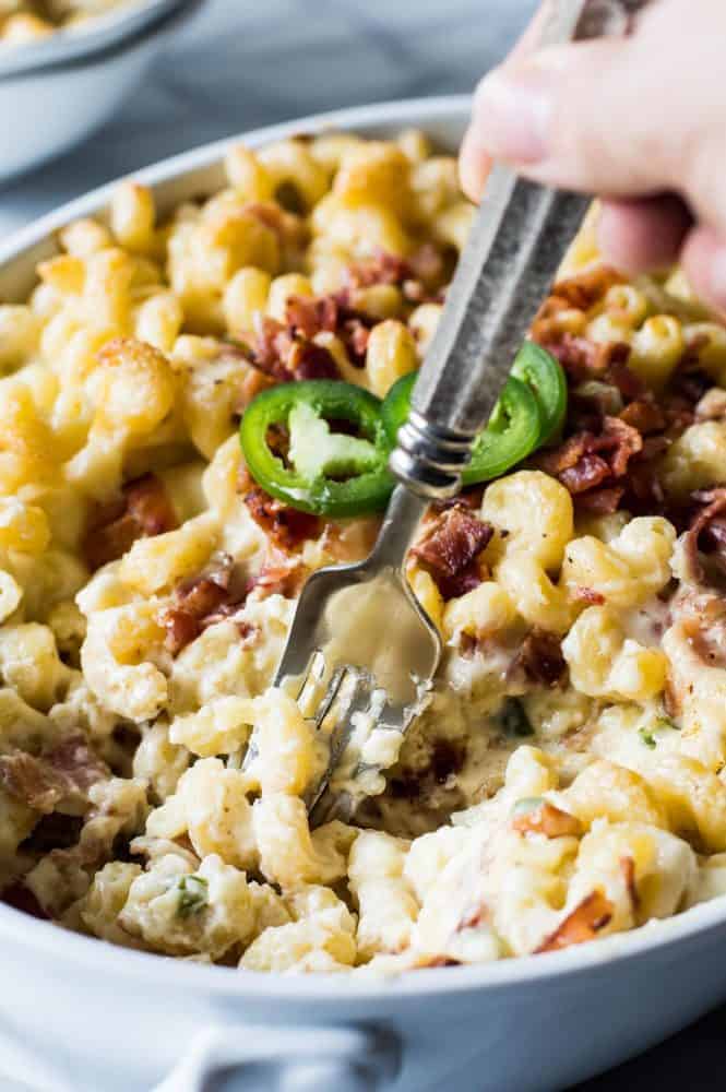 Jalapeño popper macaroni and cheese in a white casserole dish with a fork in it. 