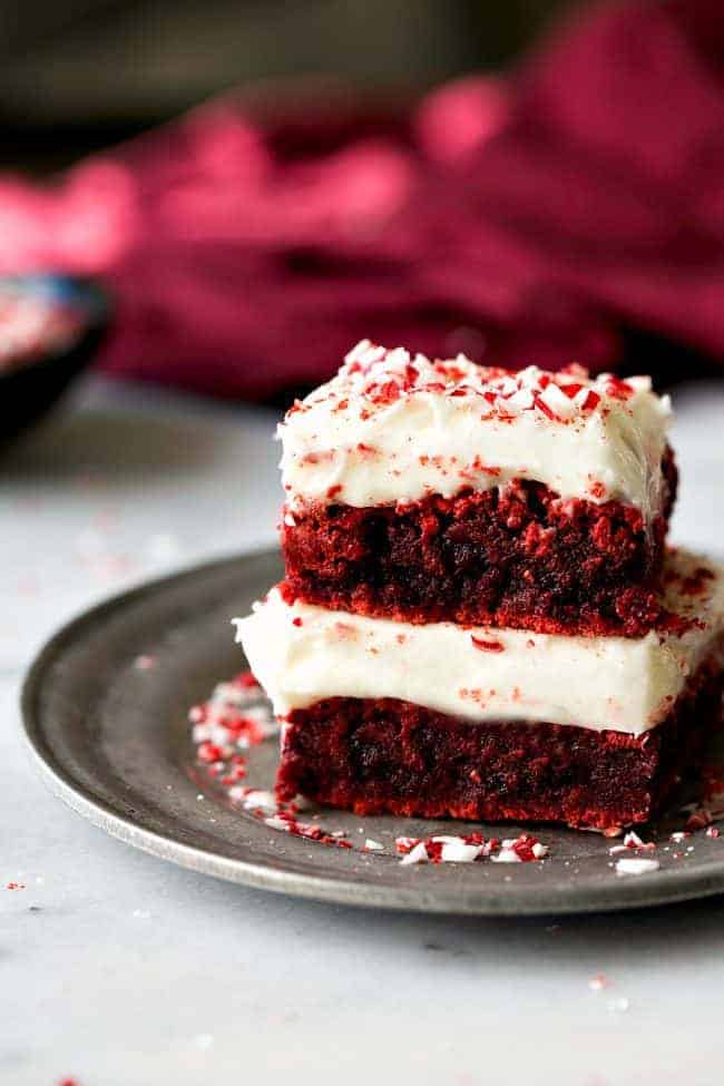 Red velvet peppermint brownies with peppermint cream cheese frosting stacked on top of each other.